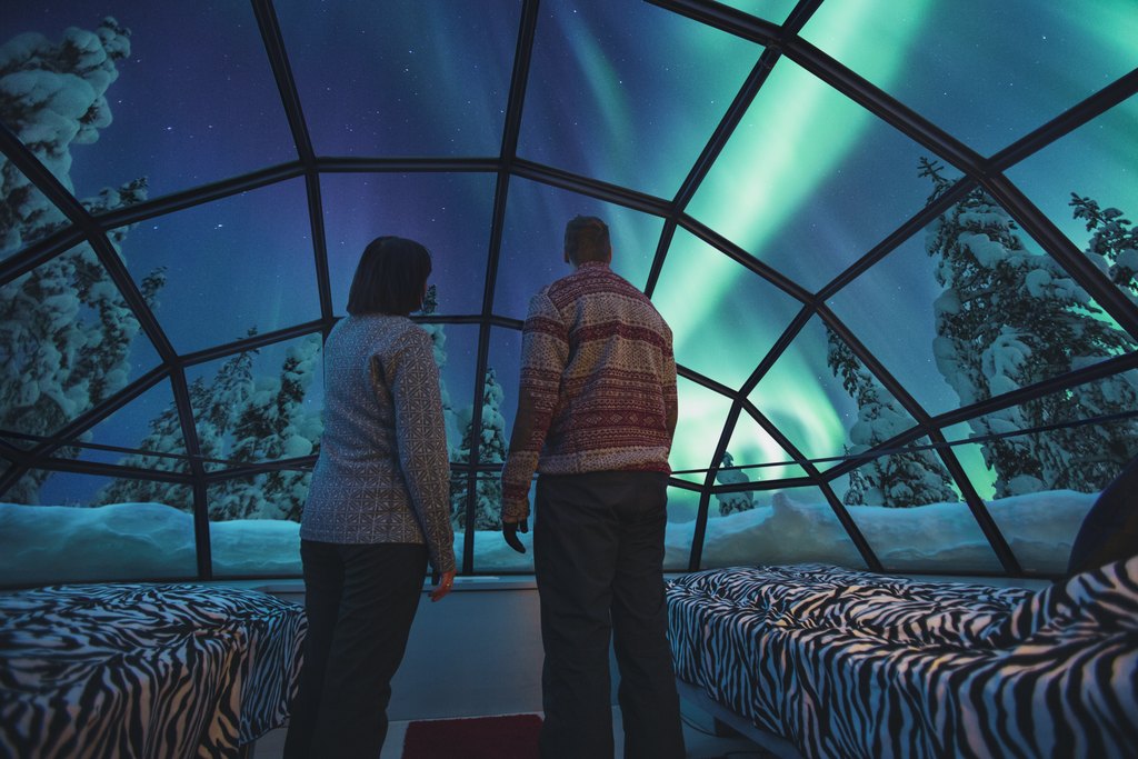 couple standing inside of the Glass igloos in Kakslauttanen Arctic Resort in Finland
