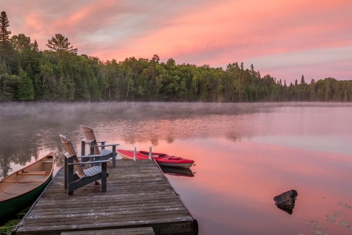 Two chairs on a Cottage Dock at sunset on a lake surrounded by trees