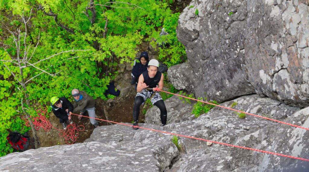 Group of teens learning to rock climb outdoors