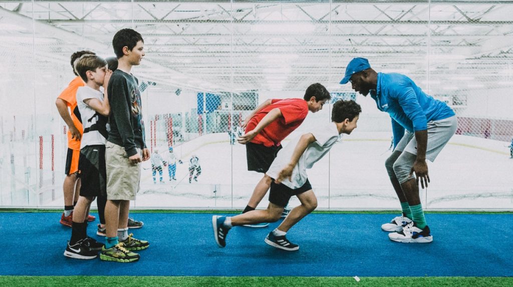 Coach with children racing in a gym class