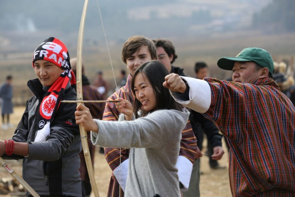 Teenagers learning archery outdoors 